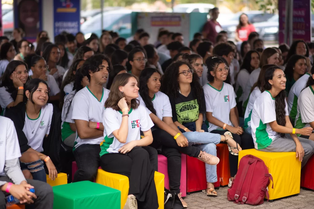 Um grupo de estudantes sentados em bancos coloridos