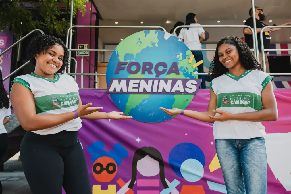 Meninas posam em frente a logo da força meninas