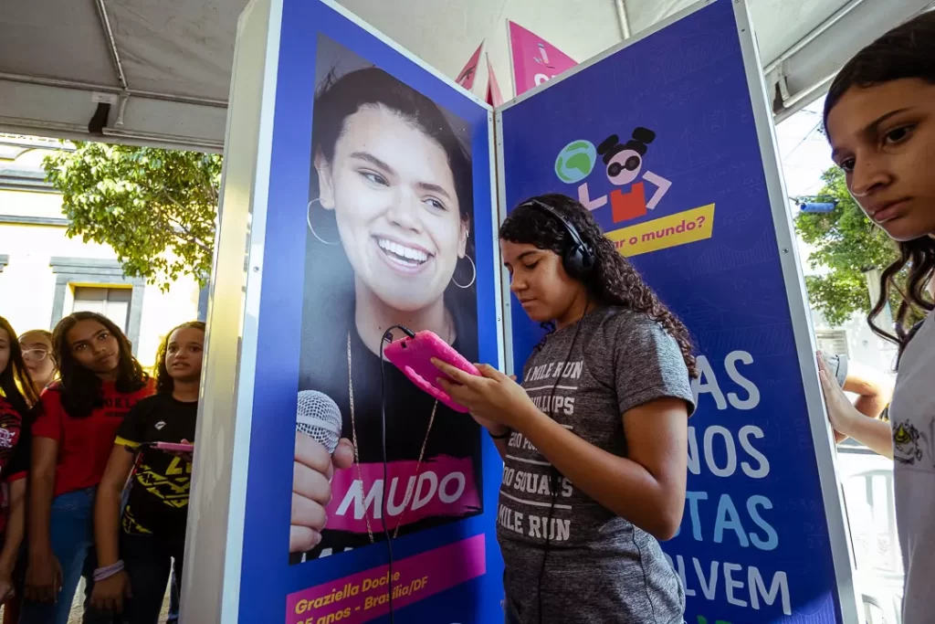 Uma menina parada na frente de um pôster com tablet na mão