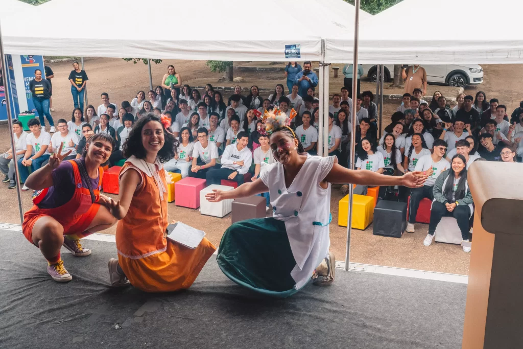 Atrizes no palco tirando foto com a plateia jovem